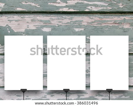 Close-up of three hanged paper sheet frames with clips on green and grey scratched wooden boards background