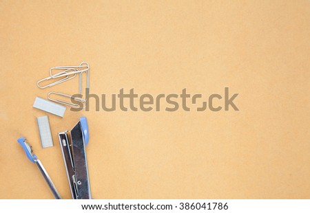 staples and stapler placed on brown paper background, leave space for copy