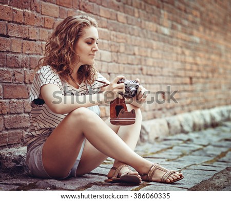Hipster portrait of pretty young woman searching for an interesting subject for his photo shooting with vintage retro photo camera