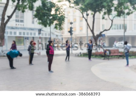 Blurred motion group of mature Vietnamese women dancing a fitness dance or line dancing/aerobics in early morning on the bank of Hoan Kiem Lake. Urban outdoor workout. Healthy lifestyle concept.
