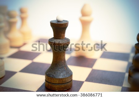 Black queen on background of white elephant on chessboard. Concept, selective focus, close up view. Soft vintage toning.