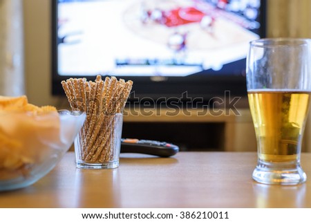 Television, TV watching (basketball game) with snacks and alcohol lying on table - stock photo
