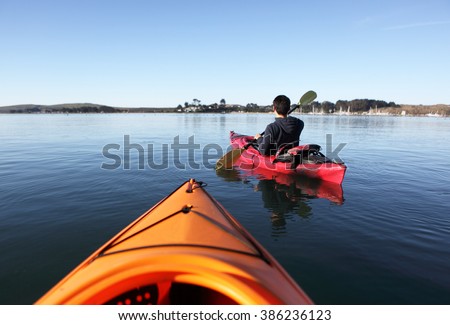 A man and a red kayak in a bay with an open view. Bodega Bay, California