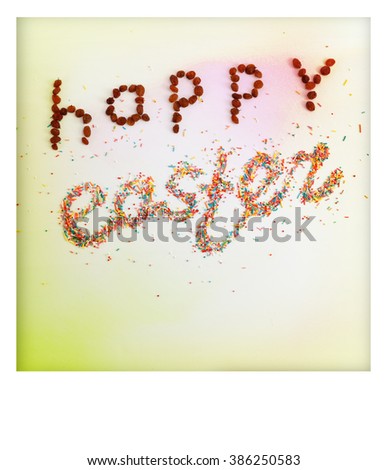 Happy Easter phrase made from raisins and colorful baking sugar over colorful background with copy space and white frame, top view