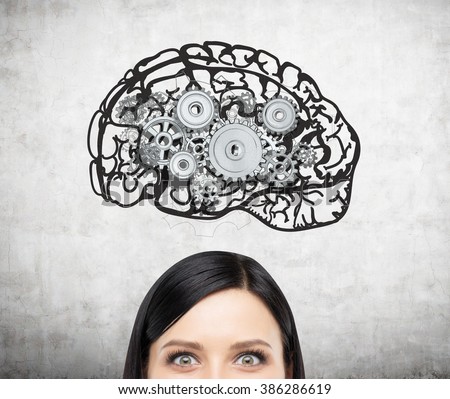 Image of brain with gears on concrete wall over woman's head. Only eyes seen. Concept of mental work.