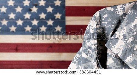 Close up of military uniform with painted rustic boards of USA flag in background.  