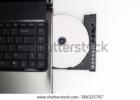 CD or DVD disc in CD-ROM  with Laptop computer on white background,Top view Royalty-Free Stock Photo #386325787