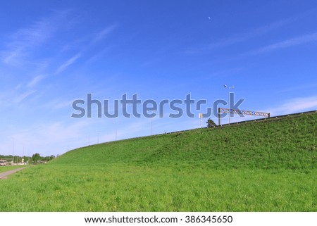 Pure blue sky, bright green lawn and road on hill at summer sunny day