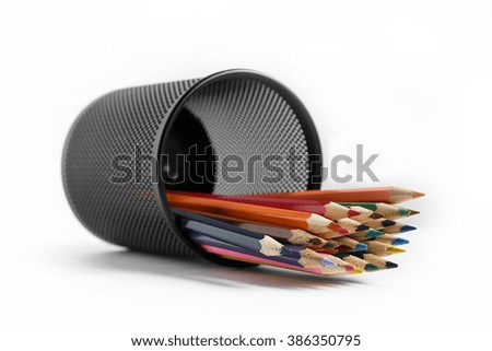Colored pencils in a metal glass on a white background