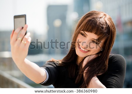 Young woman taking selfie with phone camera at street