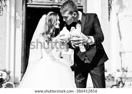 Happy newlyweds with doves at hand background church