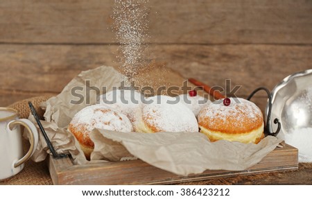 Delicious sugary donuts with red currant on wooden background