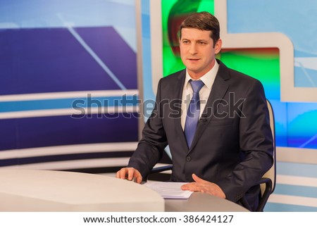 Male anchorman in tv studio. Live broadcasting Royalty-Free Stock Photo #386424127