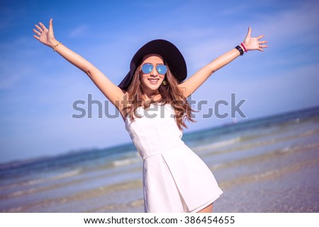happy pretty woman smiling in the beach wearing a Black and white striped dress with the sea and horizon in the background