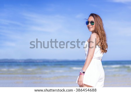happy pretty woman smiling in the beach wearing a Black and white striped dress with the sea and horizon in the background