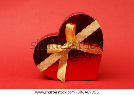 box in heart shape with bow on red background