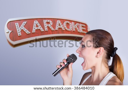  Girl with a microphone on the background of sign of karaoke.