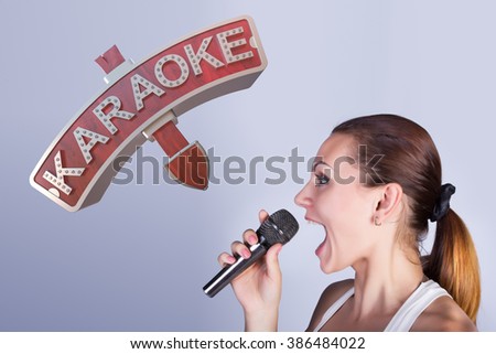  Girl with a microphone on the background of sign of karaoke.