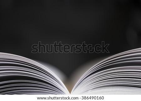 Open book with narrow depth of field with black background. Space for text above the magazine