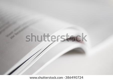 Open magazine with narrow depth of field. Magazine lies diagonally on a white surface