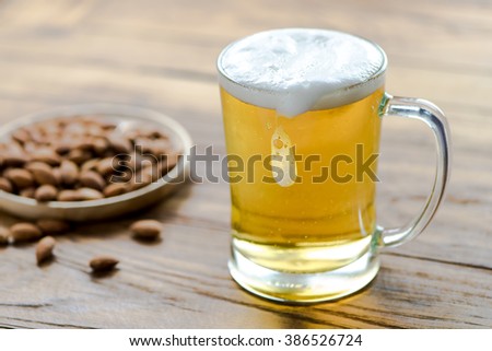 Beer in mug on wood table with almond