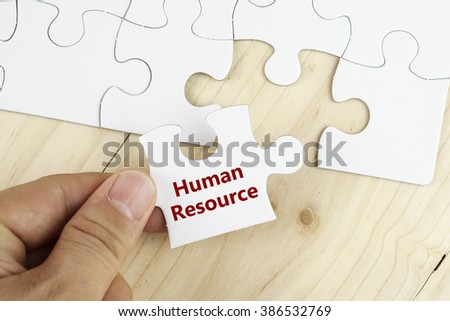 Business concept.Hand holding piece of jigsaw puzzle with word HUMAN RESOURCE on it.