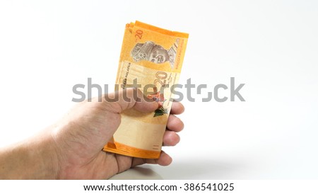 Hand holding, counting or giving away Ringgit Malaysia currency bank notes. Concept of bribery and monetary profit. Slightly de-focused and close-up shot. Copy space.
