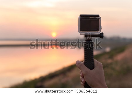 hand holding extreme camera take photo during sunset
