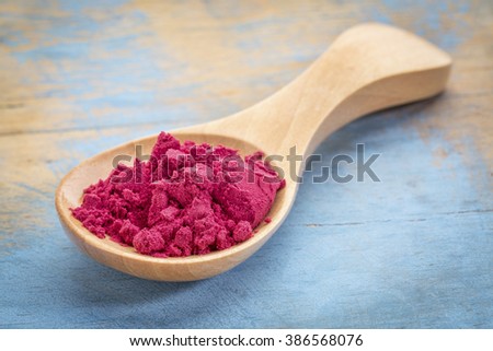 aronia berry powder on a wooden spoon against blue painted grunge wood Royalty-Free Stock Photo #386568076