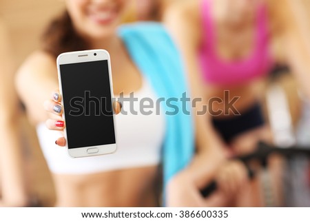 Picture of fit woman holding smartphone in gym