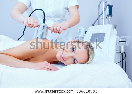 Hardware cosmetology. Picture of happy young woman getting cavitation procedure in a beauty parlour.