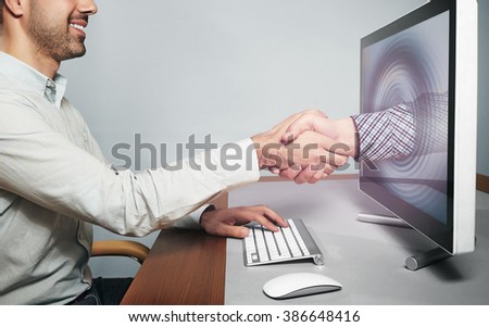 Hand reaching out from screen  to shake hand Royalty-Free Stock Photo #386648416