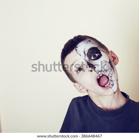 little cute boy with facepaint like skeleton to celebrate halloween