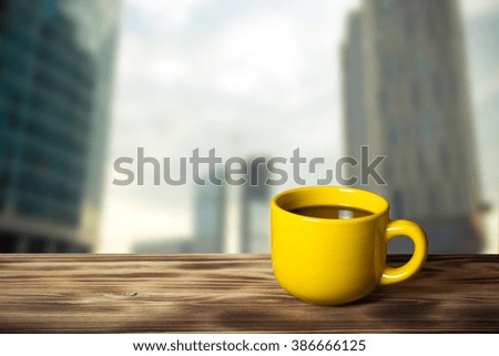 Coffee in cup on wooden table opposite a defocused cityscape for background. Collage. Selective focus. Toned.