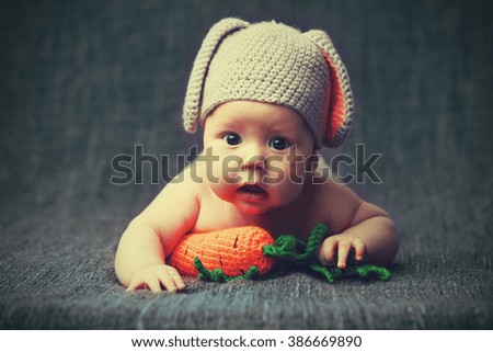 happy baby child in costume a rabbit bunny with carrot on a grey background