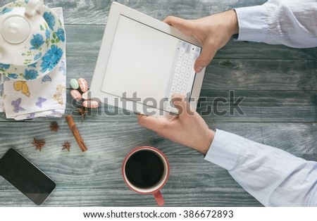 hand using mockup tablet similar to ipad style on wood desk white display with clipping path screen easy add image