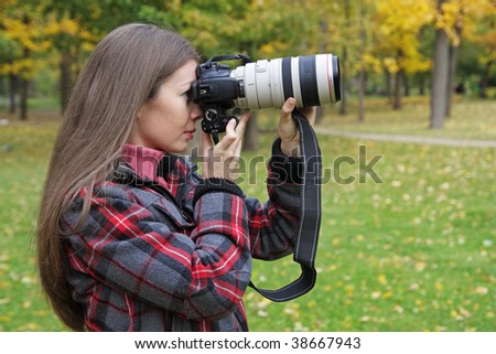The girl with the camera photographs an autumn landscape