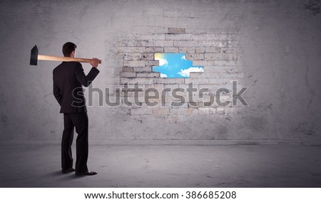 Business man hitting grungy brick wall with hammer