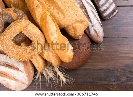 Close up of various types of whole baked bread loaves on mahogany wooden table with copy space