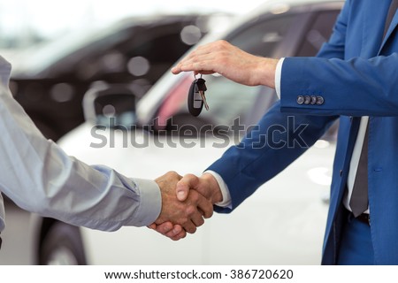 Handshake of two businessmen when selling a car in a motor show, close-up Royalty-Free Stock Photo #386720620