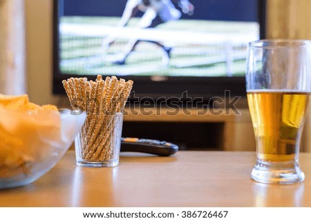 Television, TV watching (tennis match) with snacks and alcohol lying on table - stock photo