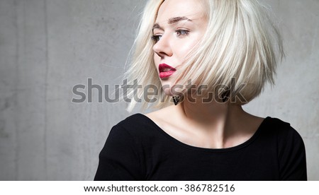 Close-up portrait of a beautiful blonde with red lips on a gray background