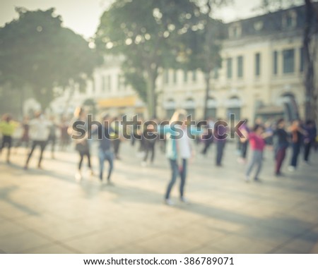Blur background group of people dancing a fitness dance or line dancing/aerobics at Ly Thai To Park Hanoi, Vietnam. Healthy lifestyle concept. Nature outdoor workout.Beautiful early morning warm light