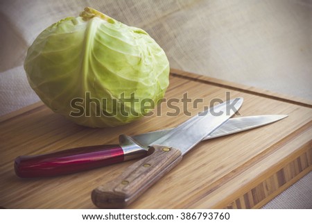 Cabbage on a serving board with a knife, a book with recipes and a soft light.
