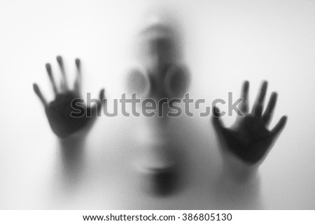 Woman wearing a gas mask behind the frosted glass Royalty-Free Stock Photo #386805130