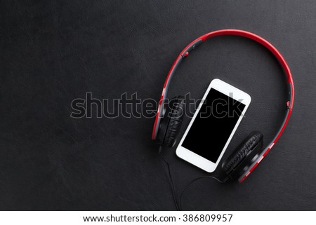 Headphones and smartphone on leather desk table. Top view with copy space