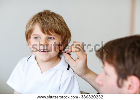Father painting flag on face of little son for football or soccer game. Kid boy fan happy about game of team in champions league. Selective focus