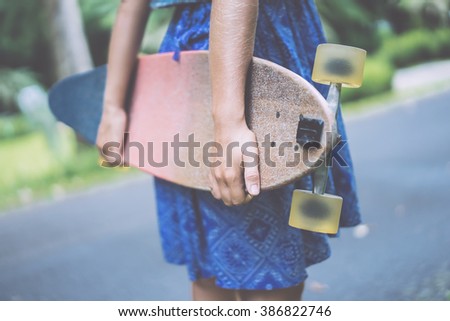 beautiful girl with skateboard. girl holding a skateboard in hands. Longboard in the hands of a girl in a dress. girl in the park with longboard in the hands of