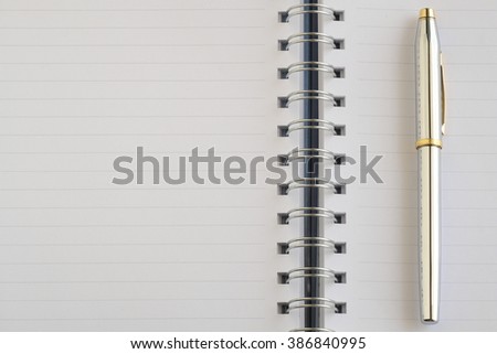 The blank notebook and a silver pen.