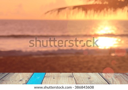 Blur palm leaf on tropical sunset beach with bokeh wave on old empty wood table background.Product display in nature.